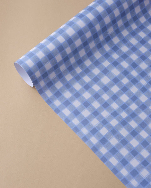 Roll of blue and white checkered paper on a beige background