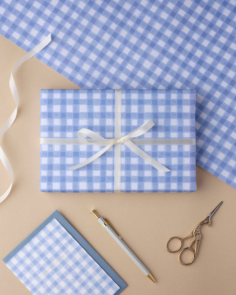 Gift wrapped in blue and white gingham paper with scissors and ribbon. Plastic free gift wrap, designed and printed in the UK. 