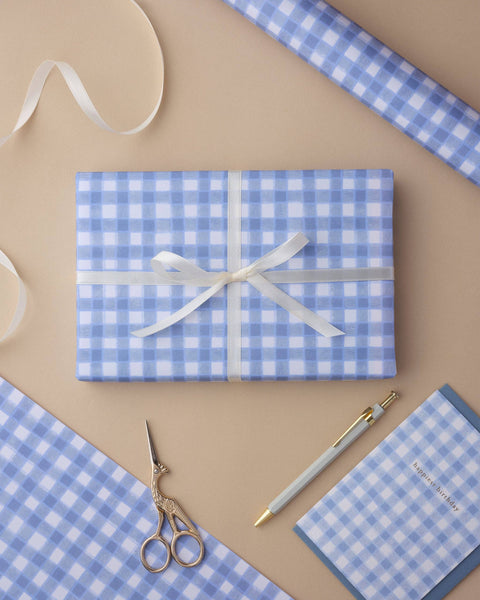 Gift wrapped in blue checkered paper with a white ribbon on a beige background.